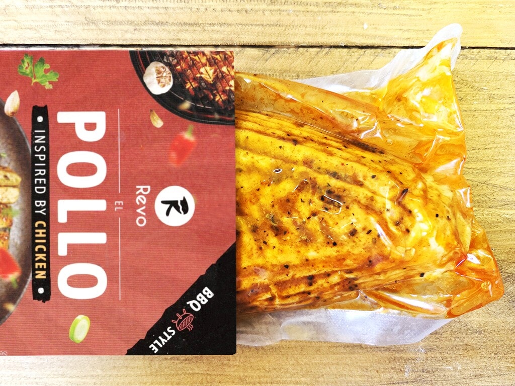 Revo | El Pollo | Herzschatz Red Pollo packaging beside a vacuum-sealed marinated chicken on a wooden table.