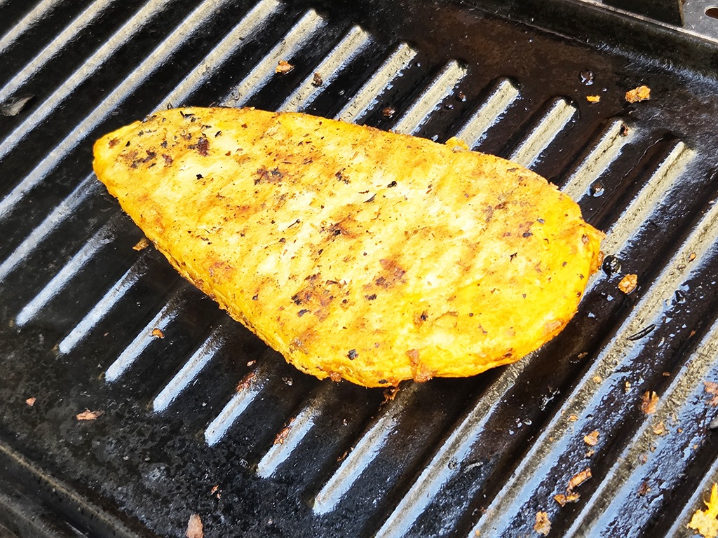 Revo | El Pollo | Herzschatz Grilled chicken breast with golden-brown char marks on a ridged grill pan.