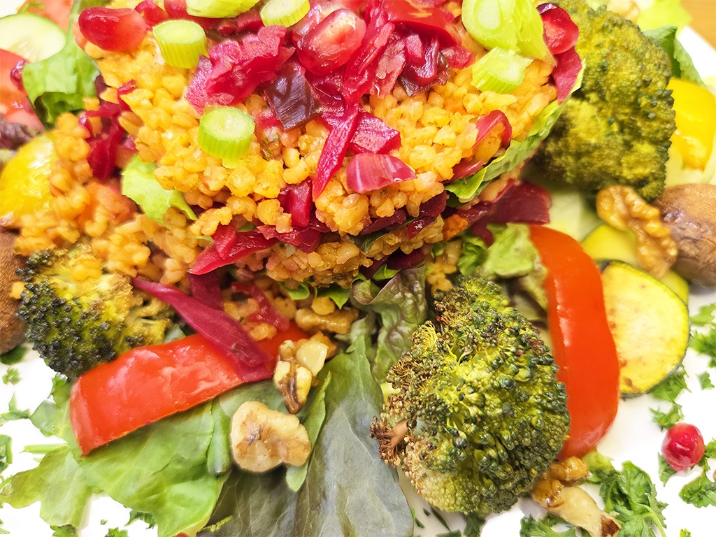 Hengstenberg | Bulgur Salat mit Tomate und Karotte | Herzschatz Colorful veggie plate with a grain-topped salad perched on mixed greens, plus broccoli, red peppers, zucchini, and walnuts.