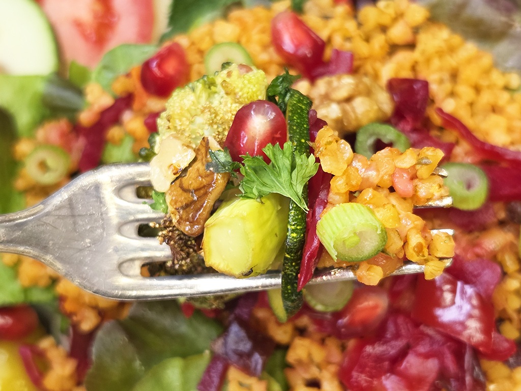 Hengstenberg | Bulgur Salat mit Tomate und Karotte | Herzschatz Forkful of a colorful grain salad with bulgur, cucumber, olives, cherry tomatoes, beets, zucchini and parsley on a fork
