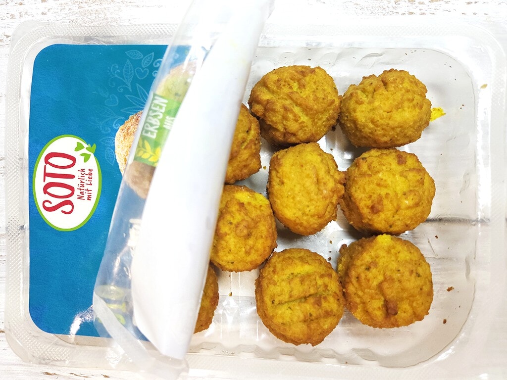 SOTO | Falafel Traditionell | Herzschatz Takeout container with eight golden fried balls (falafel) in a clear tray, lid slightly open near a blue SOTO label.