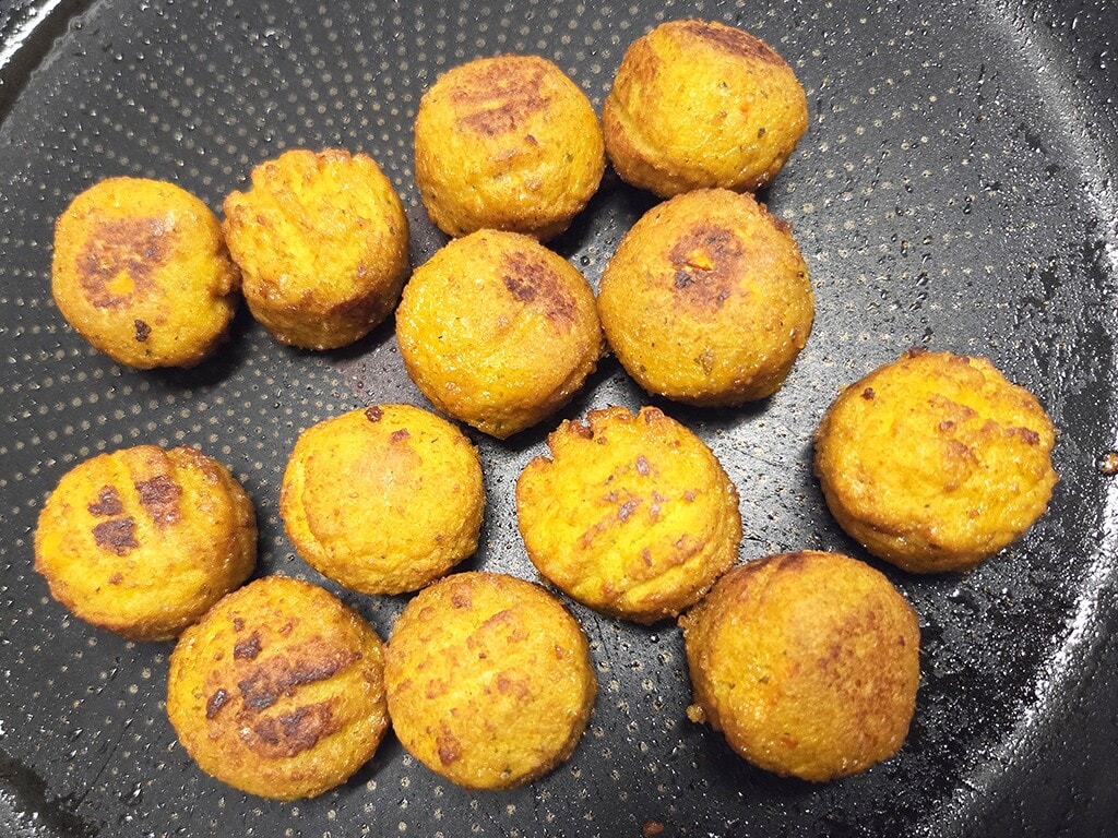 SOTO | Falafel Traditionell | Herzschatz Golden-orange falafel balls browning in a black nonstick skillet.