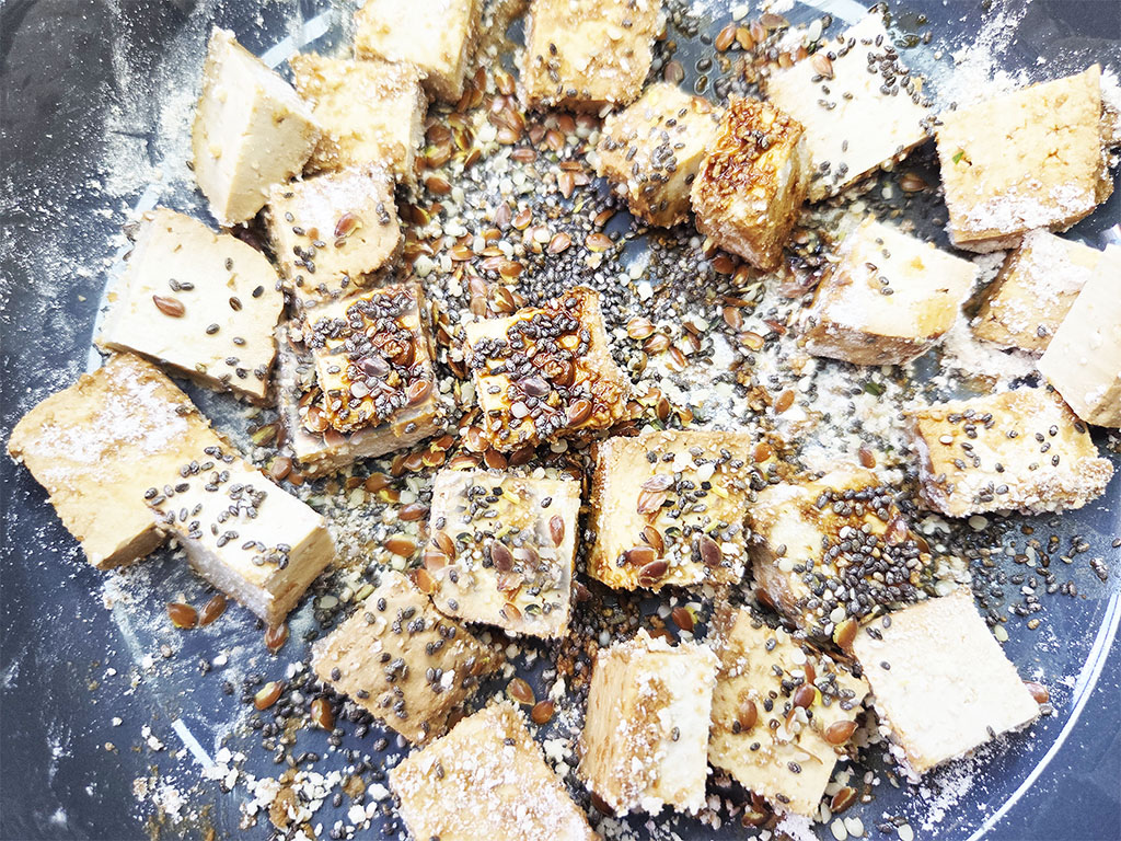 Tofoo & Co | Smoked Tofu | Herzschatz Cubes of fried tofu in a skillet, sprinkled with sesame seeds.