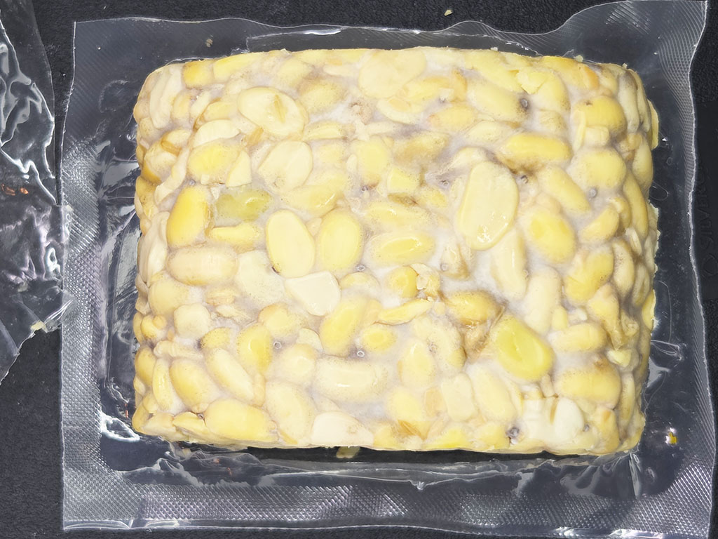 Square block of yellow corn kernels embedded in clear gelatin inside a plastic tray (packaged food)