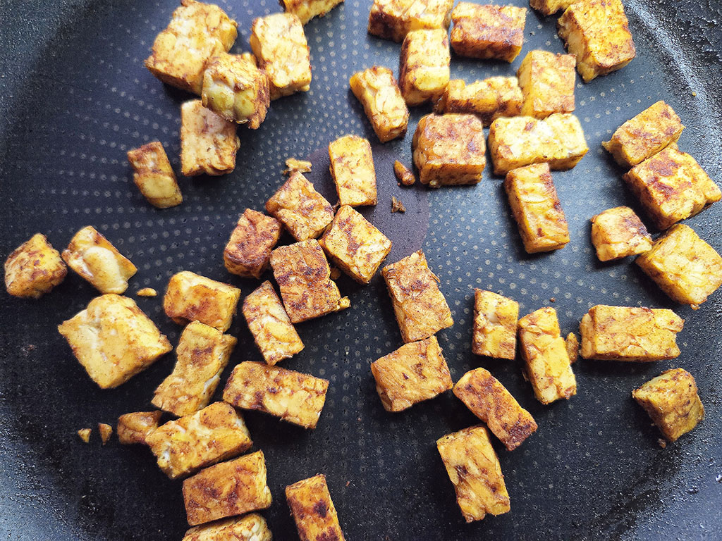 Small golden-brown fried tofu cubes scattered in a frying pan.