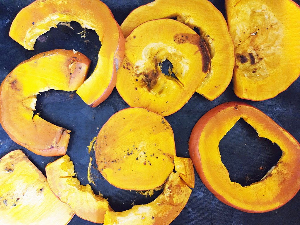 Planted. | Filet-Würfel a la mexicana | Herzschatz Bright orange mango slices arranged on a dark surface, some pieces peeled and broken.