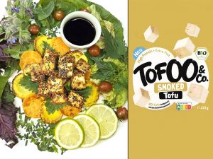 Two-panel image: left shows a plate of roasted sweet potato bites with greens, lime slices, and a small cup of dark sauce; right shows Tof00 & Co Smoked Tofu packaging on a mustard background.